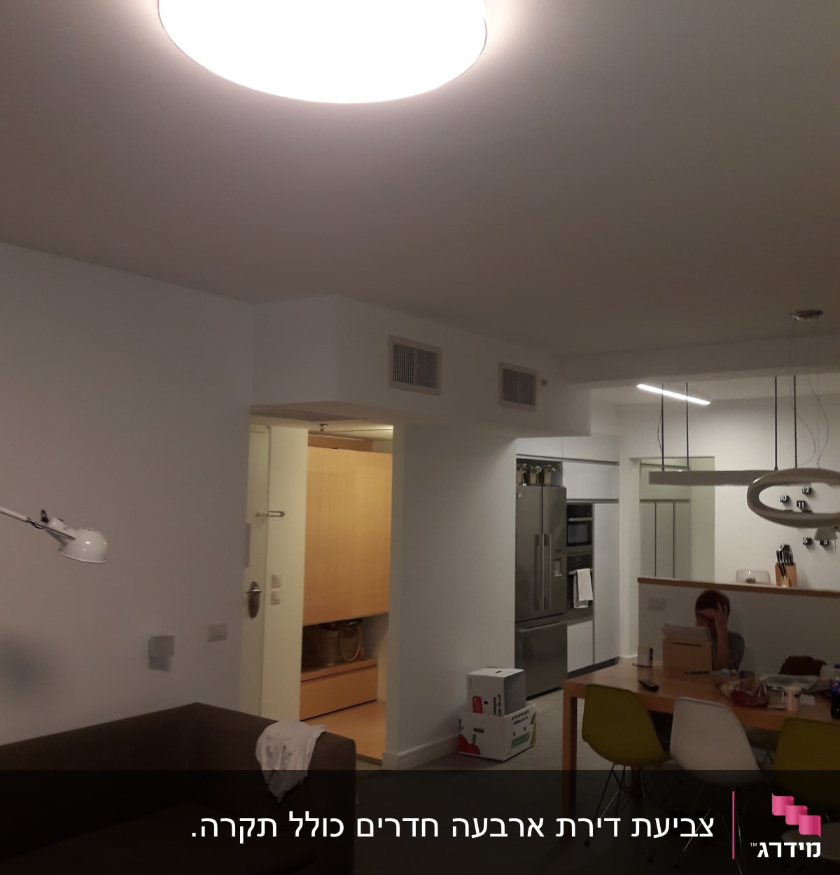 חדר עם תאורה עליונה, שולחן וכיסאות צבעוניים